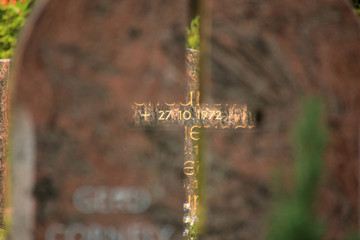 Kreuz in einem Grabstein mit Blick auf ein Sterbedatum