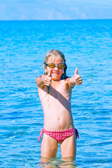 happy girl in swimming glasses comes out of the water to the sea, Greece