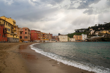Fototapeta na wymiar Scenic view of the Bay of Silence in the old fishing village of Sestri Levante with the typical colored houses leaned out on the beach with sun rays filtering through clouds, Liguria, Italy