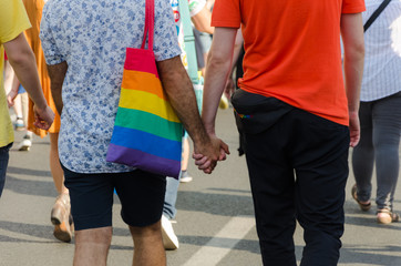 Gay young couple walking away together holding hands. Gay couple.