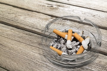 Ashtray and smoked cigarettes on wooden background