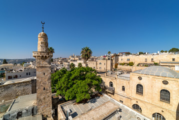 Fototapeta premium Old minaret among typical houses under blue sky in Old City of Jerusalem, Israel (view from above).