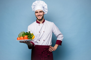 Food service, organic food, healthy diet, cooking and professional culinary concept - chef in white uniform holds vegetables.
