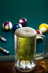 a frozen beer mug with foam on a green billiard table, frozen, cold beer