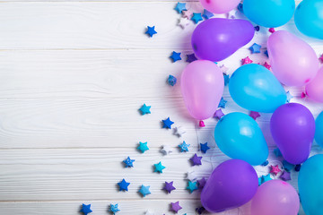 Bunch of colorful party balloons with paper stars on white wooden background