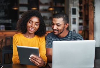 Young couple with laptop and digital tablet in café