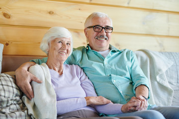 Cheerful mature spouses in casualwear watching program