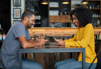 Couple at cafe table using mobile phones