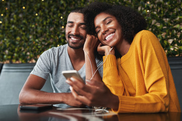 Young couple enjoying listening music on earphones