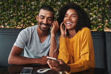 Young couple sharing earphone for listening music on mobile phon