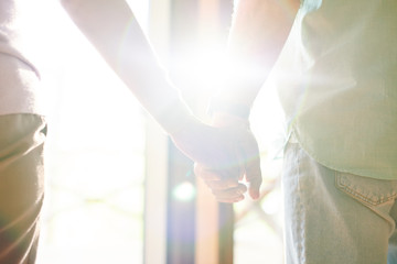 Flare of sunlight between hands of casual senior spouses