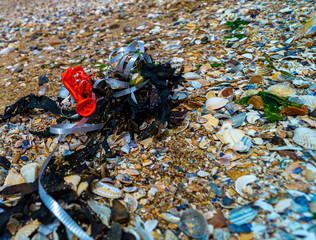 close up of plastic balloon and ribbon string wash up and weathered on beach, save our oceans, pollution in the waters and ocean