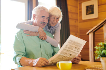 Cheerful senior couple in casualwear looking through latest news