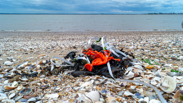 close up of plastic balloon and ribbon string wash up and weathered on beach, save our oceans, pollution in the waters and ocean