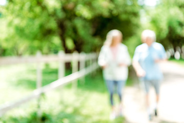 blurred view of retired man running near senior wife in park