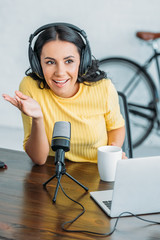 cheerful radio host gesturing while speaking in microphone in studio