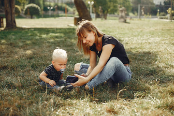 Naklejka na ściany i meble Family in a summer park. Mother in a black t-shirt. Cute little boy