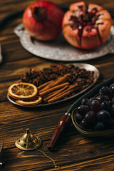 selective focus of cinnamon, garnets, grapes and hookah on wooden surface