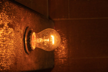 Electric incandescent lamp. Yellow light, dark wood, plastic, glare. Concept of vintage lighting.