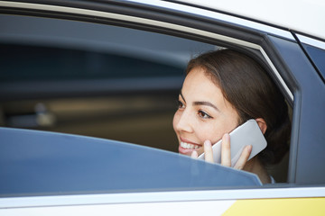 Side view portrait of beautiful woman speaking by phone in car looking out of window, copy space