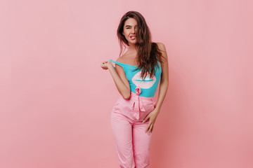 Beautiful dark-haired young woman expressing happy emotions. Studio shot of graceful girl in pink...