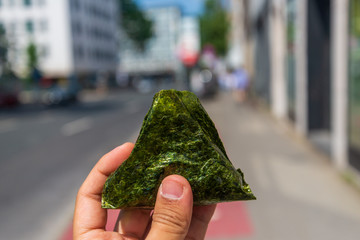 Hand hold Onigiri, popular Japanese rice ball wrap with Nori seaweed filled with ingredient, with...
