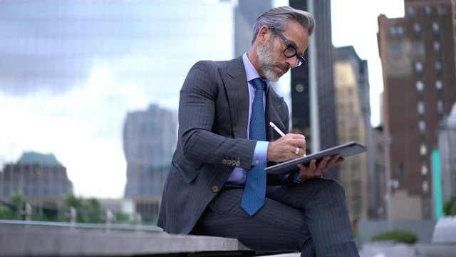 Concentrated proud ceo in formal wear searching information for project using pen stylus on touch pad, experienced finance manager using app on digital tablet for working with budget accounting 