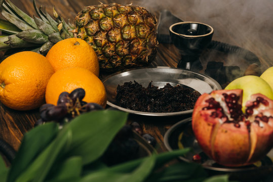 hookah, tobacco, apples, grapes, oranges, garnet and pineapple on wooden surface