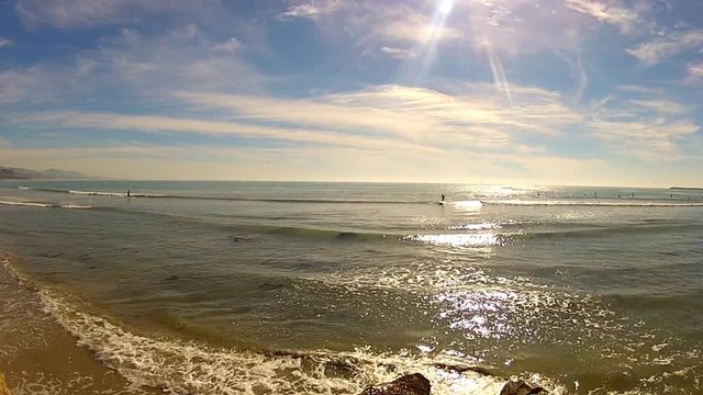 Distant Surfers Riding Ocean Waves In California