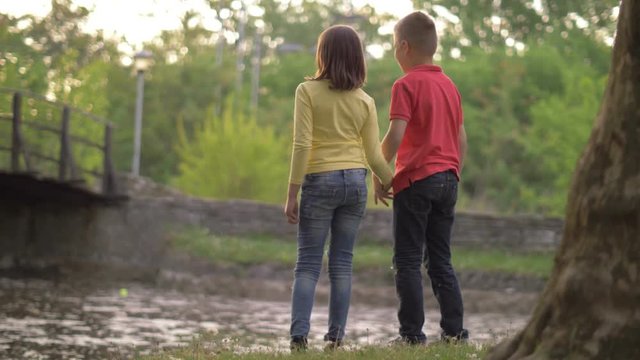Young boy and girl is holding hands at golden sundown