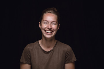 Close up portrait of young woman isolated on black studio background. Photoshot of real emotions of...