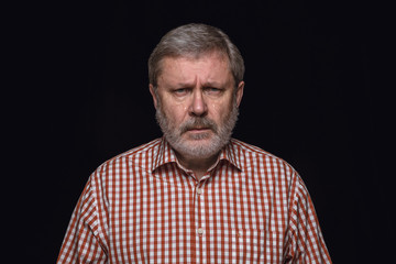 Obraz premium Close up portrait of senior man isolated on black studio background. Photoshot of real emotions of male model. Crying, sad, dreary and hopeless. Facial expression, human emotions concept.