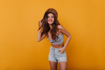 Wonderful sporty girl with long hairstyle smiling on yellow background. Cute european female model with tanned skin enjoying photoshoot in studio and laughing.