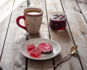Sweet lunch with cranberry marshmallow and marmalade, green tea in a large ceramic mug on a wooden table