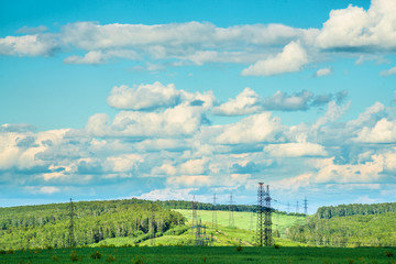 Fototapeta na wymiar High voltage transmission towers on green grassland at sunny summer day 
