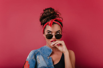 Wonderful brunette girl in casual outfit thoughtfully posing on claret background. Indoor photo of joyful caucasian lady with brown eyes and red ribbon in hair.