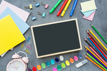 School supplies stationery, colour pencils, paints, paper on gray concrete background, back to school concept with copy space for text, modern elementary education. flat lay, top view, mockup