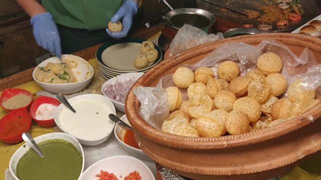 Panipuri or Golgappa is a common street snack from India. It's a round, hollow puri filled with a mixture of flavoured water and other chat items. Over colourful or wooden background. Selective focus