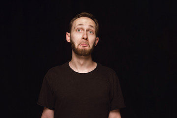 Close up portrait of young man isolated on black studio background. Photoshot of real emotions of male model. Wondering, exciting and astonished. Facial expression, human emotions concept.