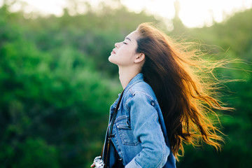 Happy Asian tourist with vintage camera and blowing her hair with nature background and rim light.