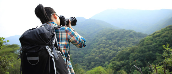 Woman photographer taking photo on morning mountain forest