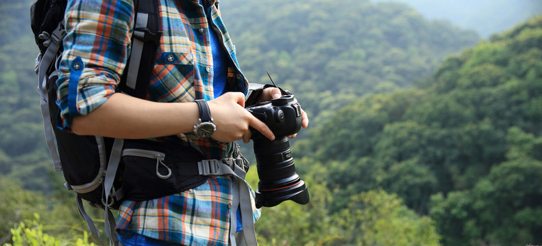 Woman photographer taking photo on morning mountain forest