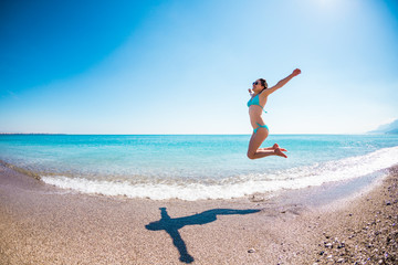 Fototapeta na wymiar Girl in a bathing suit jumping on the beach.