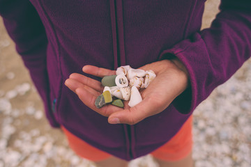 The girl collects sea stones and shells.