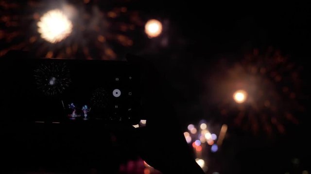 Hands of woman recording video fireworks show with smartphone