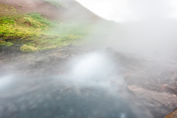 Closeup of steam geyser in Deildartunguhver hot springs in Iceland with long exposure cloudy mist fog coming out of cave boiling water vapor