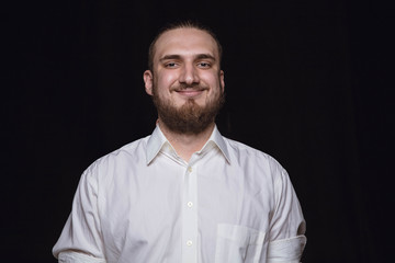 Obraz premium Close up portrait of young man isolated on black studio background. Photoshot of real emotions of male model. Smiling, feeling happy. Facial expression, pure and clear human emotions concept.