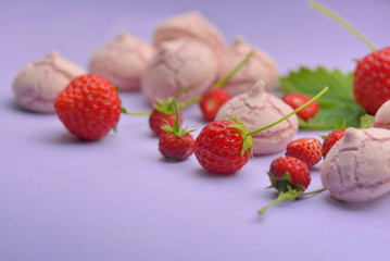 little meringues with strawberries on colored background