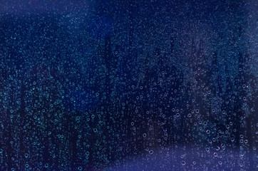 Focus and blurred photo of Rain drop on glass window with dark blue color for abstract and background concept.