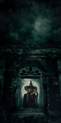 Halloween witch holding a skull standing over ancient castle window, full moon with spooky cloudy sky, Halloween mystery concept